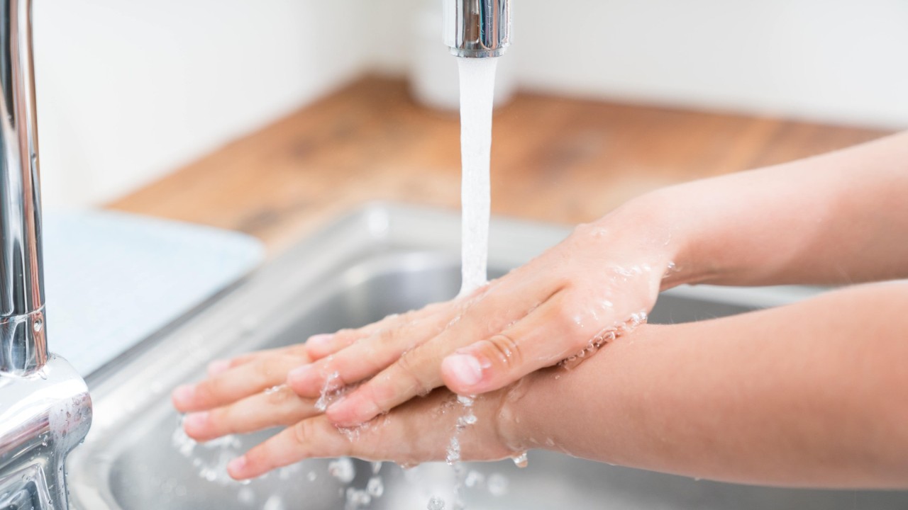 Hände unter laufendem Wasserhahn